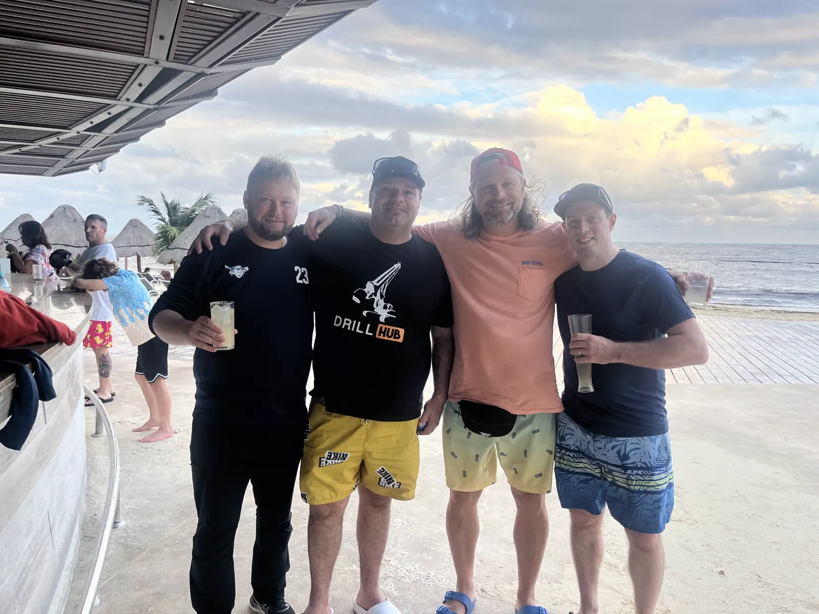 Four adult players standing arm in arm on the beach in Cancún after a game