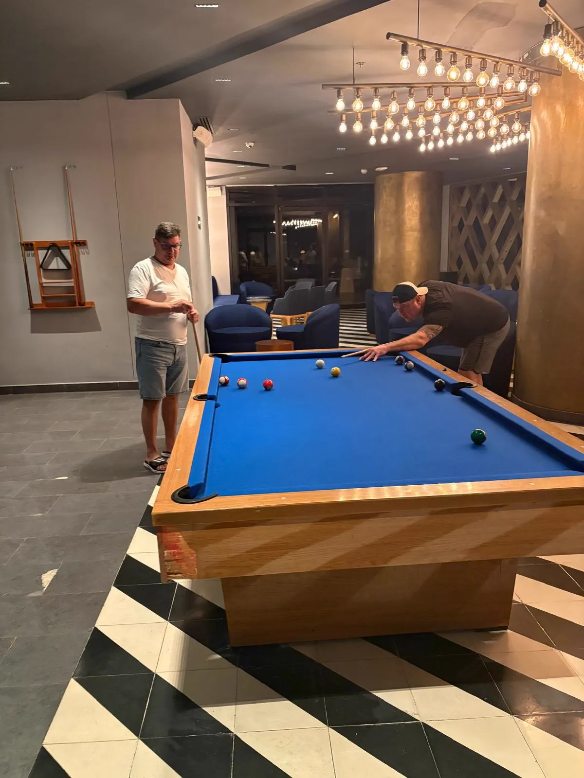 Two players shooting pool in the resort lounge at night