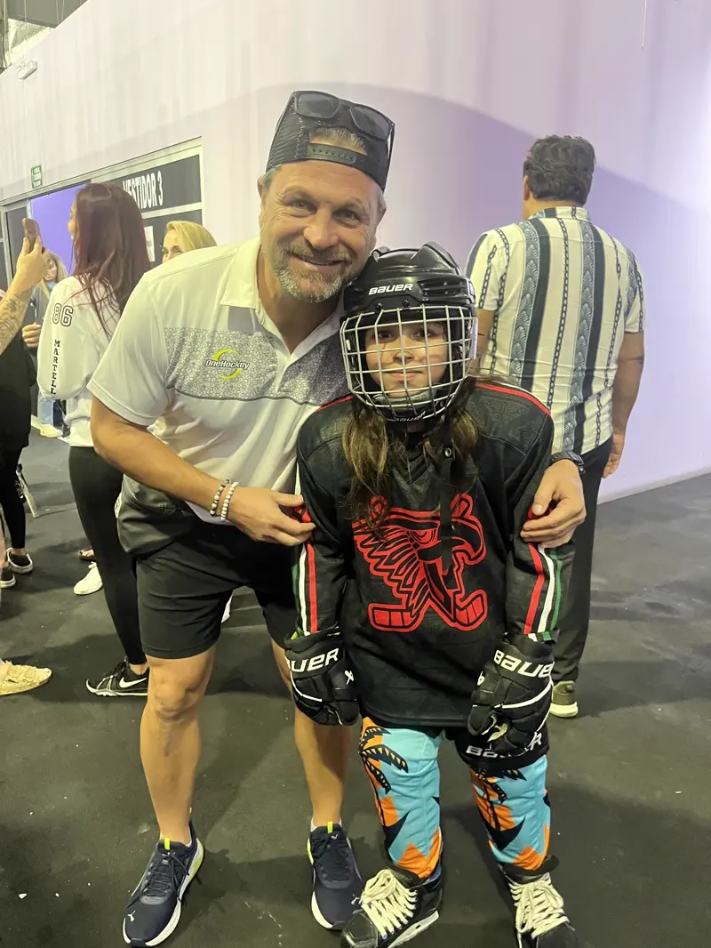 A coach with an arm around a young player in full gear at the Cancún rink