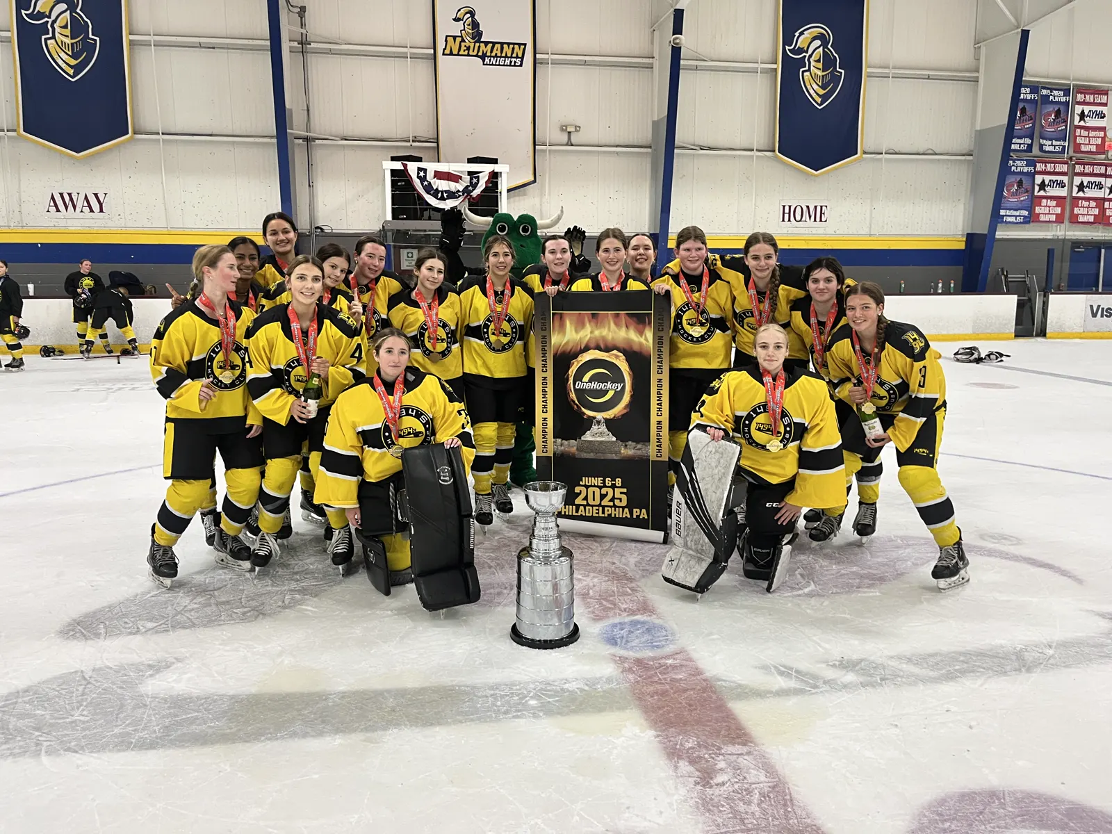A girls team on the ice with the OneHockey Cup and their championship banner