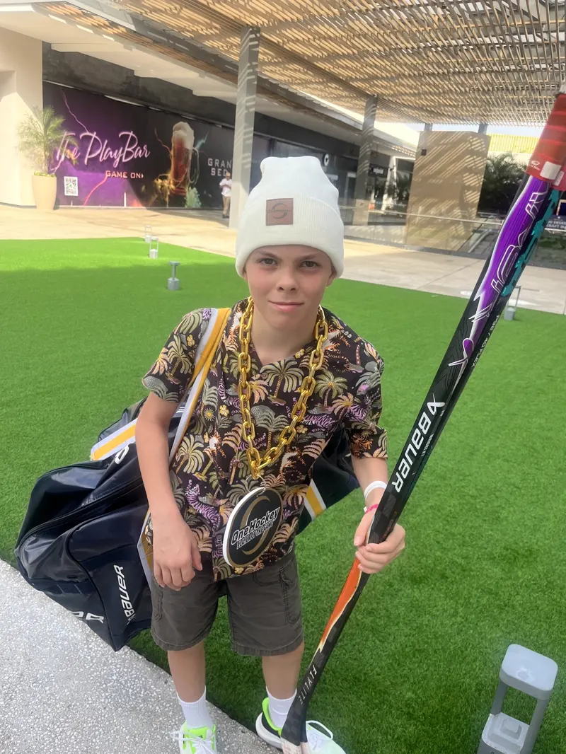 A young player carrying his bag and stick outside the outlet centre in Cancún