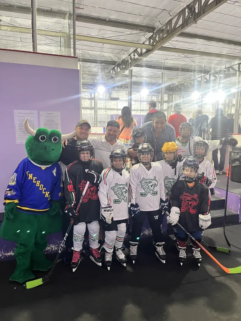 A youth team on the ice in Cancún with Freddie the mascot